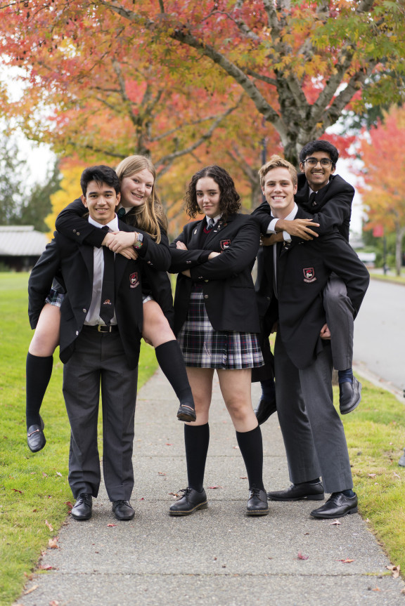 A group of students in uniform smiling and being silly together